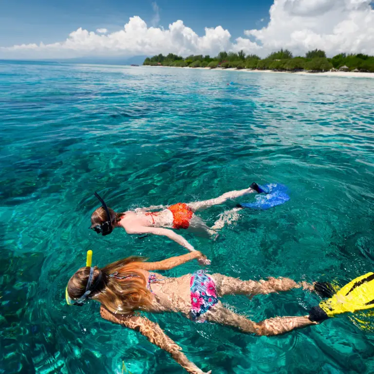 A private boat and snorkelers exploring an island cove in Boracay