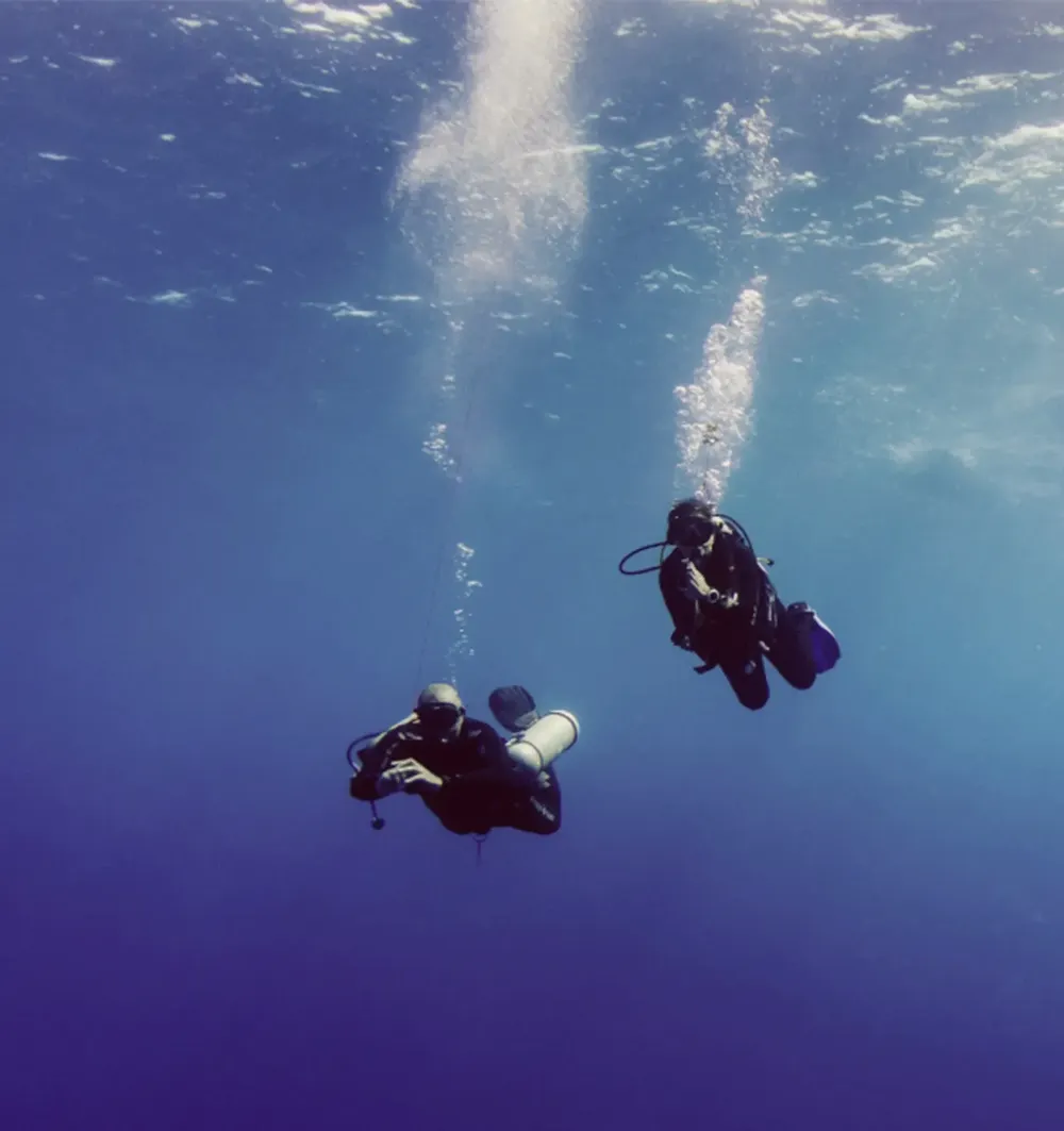 Two scuba divers descending into Boracay's deep blue water